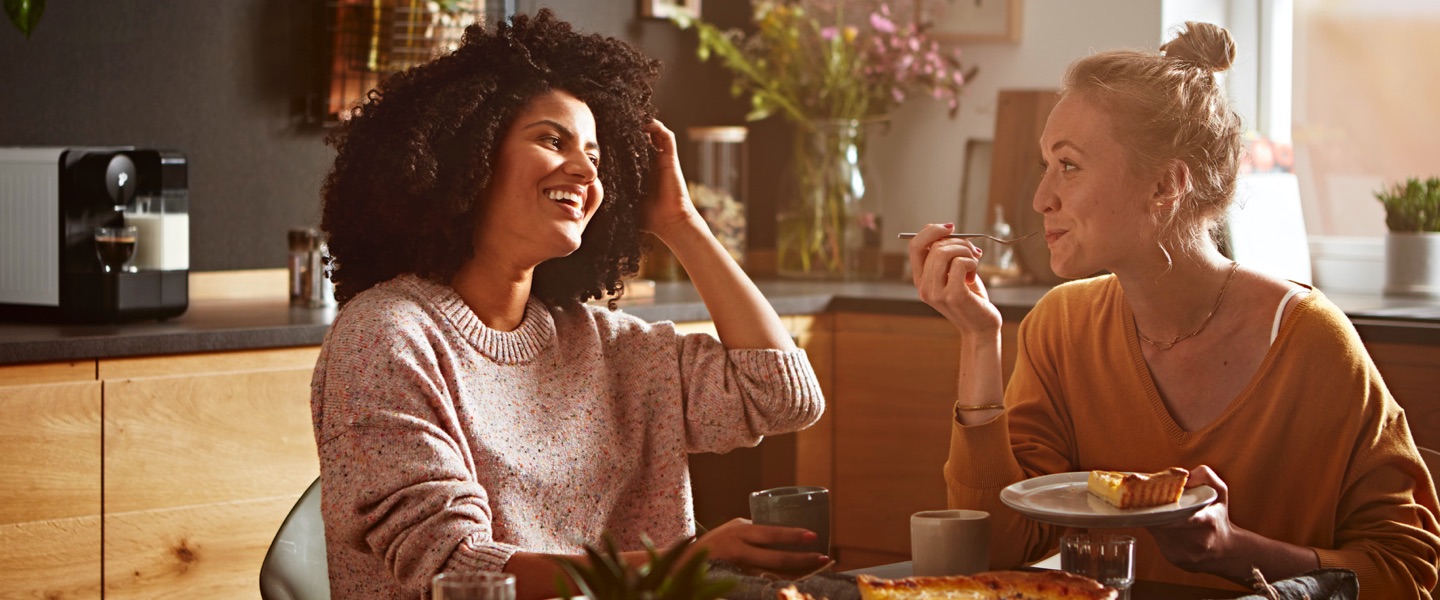 Zwei Frauen sitzen an einem Tisch mit Kaffee und Kuchen.
