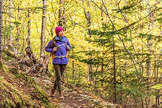 Eine Frau geht mit ihrer Outdoorjacke in einem Wald spazieren.