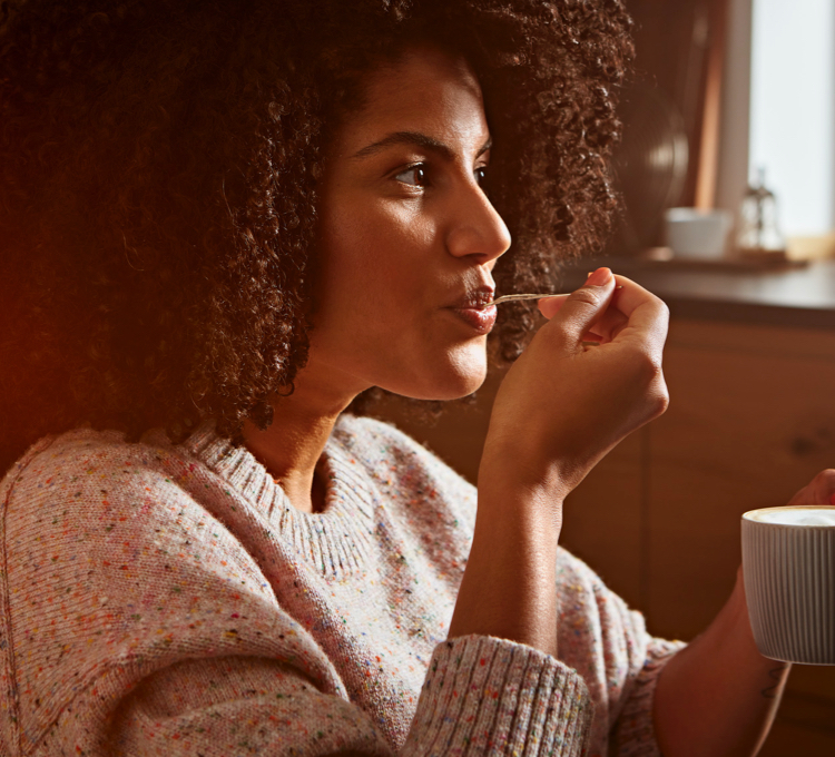 Eine Frau trinkt genüsslich einen Latte Macchiato