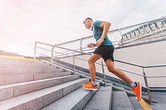 Ein Mann läuft mit seinem blauen Sportshirt eine Treppe hinauf.