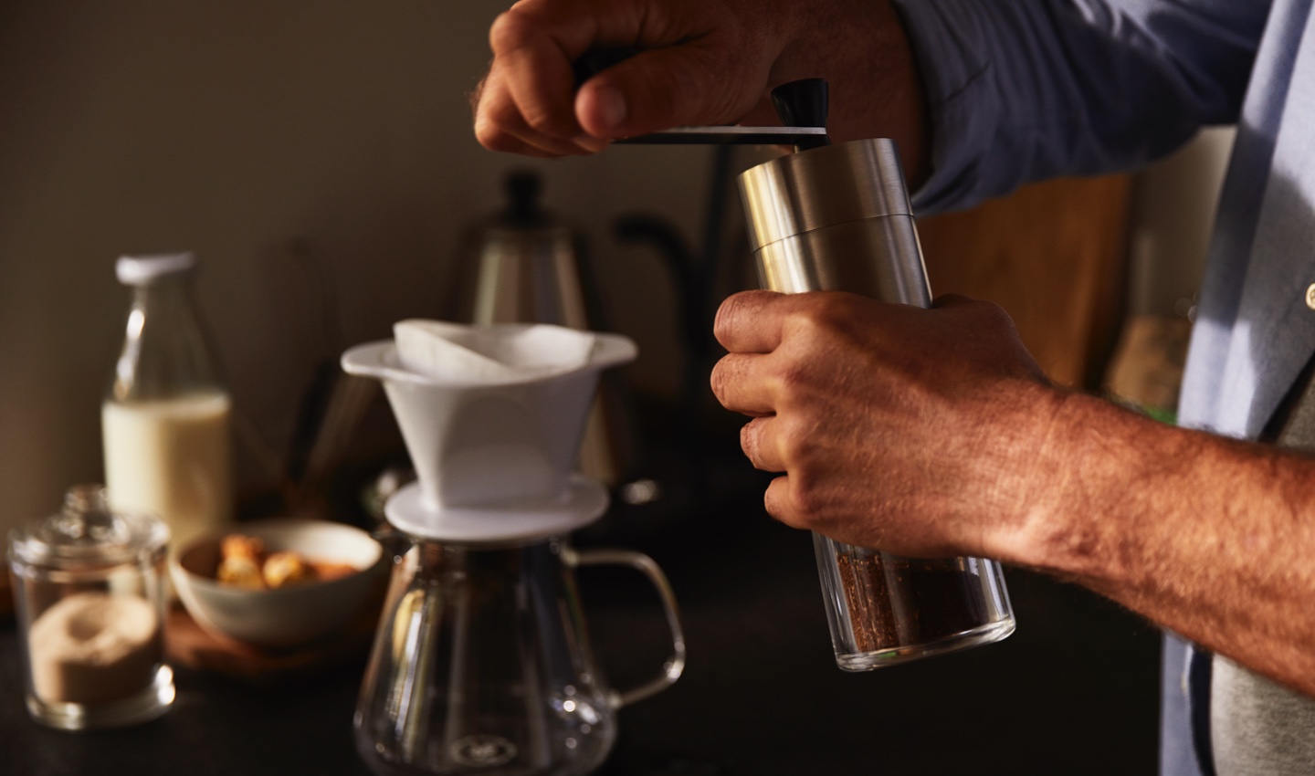 Mann mahlt Kaffee mit einer Handmühle