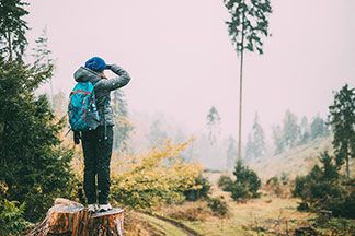 Eine Frau steht mit ihrer Outdoorhose in einem Wald.