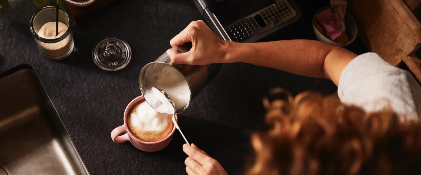 Ein kleines Mädchen schaut freudig und neugierig zu einem Mann hoch, der einen Kaffee trinkt.