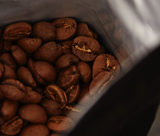 Blick in eine aufgerissene Packung mit ganzen Kaffeebohnen
