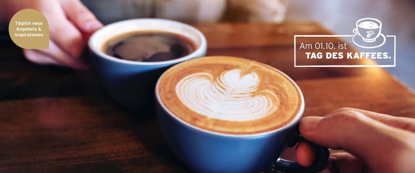 Zwei Kaffeetassen stoßen an, was auf den Tag des Kaffees verweist.