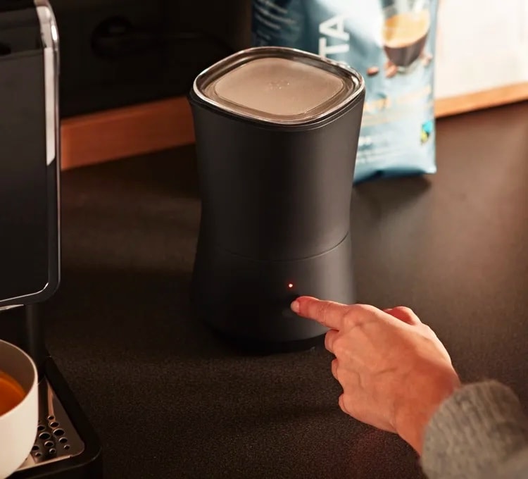 Der Elektrische Milchaufschäumer wird in einem Stimmungsvollen Bild neben einem Kaffee präsentiert.