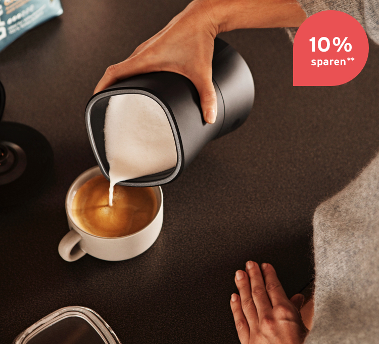 Der Schaum aus einem elektrischen Milchaufschäumer wird in den Kaffee gegeben.