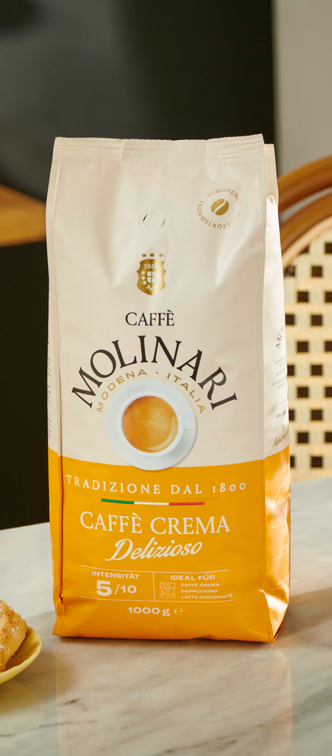 Kaffeeverpackung mit gelbem Design steht auf Arbeitsplatte aus Marmor. Daneben stehen italienische Cantuccini.