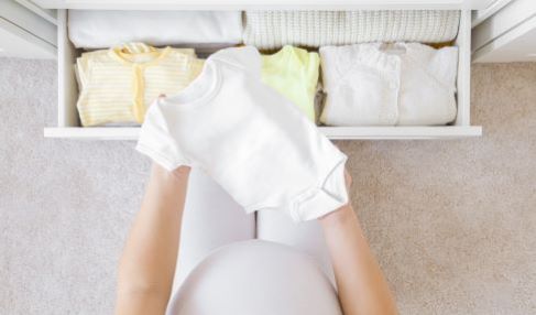 Eine Mutter öffnet die Kommode von dem Kinderkleiderschrank um Sachen für ihr Baby zu verstauen.