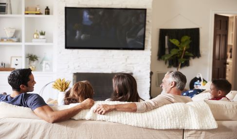 Familie sitzt auf dem Sofa vor dem Fernseher.