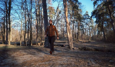 Gute Qualität: Für Wanderungen ist die Fleecejacke perfekt. Ein Mann läuft in einer hellen Jacke durch den Wald.