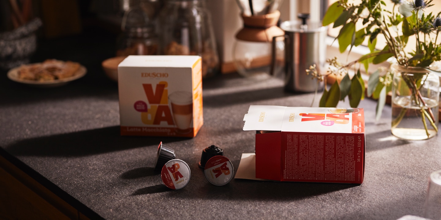 Veschiedene Eduscho Vida Kapseln liegen vor einer offenen Verpackung