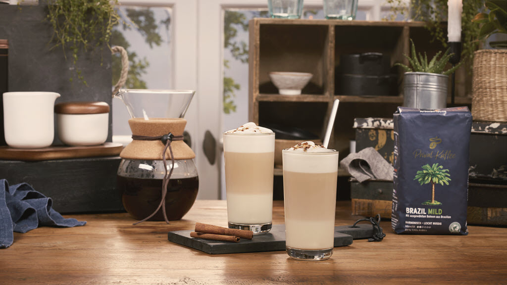 Ein zubereiteter Coffee Almond Latte mit frisch aufgebrühtem Filterkaffee im Hintergrund