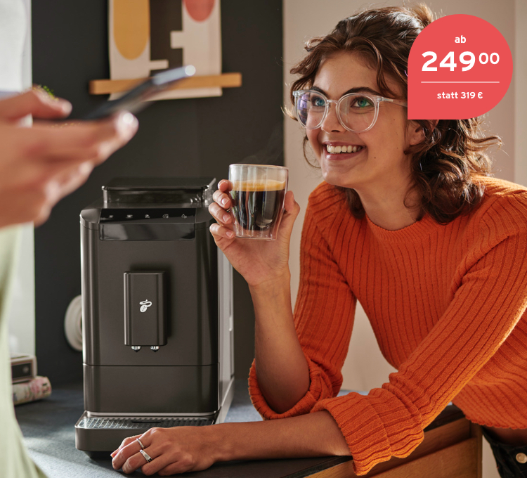 Frau steht mit einem Caffè Crema in der Hand neben dem Kaffeevollautomaten Esperto2 Caffè